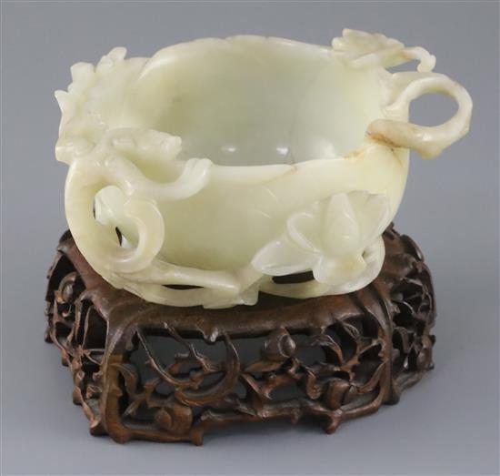 A Chinese pale celadon jade lotus cup, late Ming dynasty, W.13cm, associated wood stand